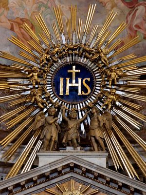 IHS monogram, on top of the main altar of the Gesù, Rome, Italy. Wikimedia Commons.