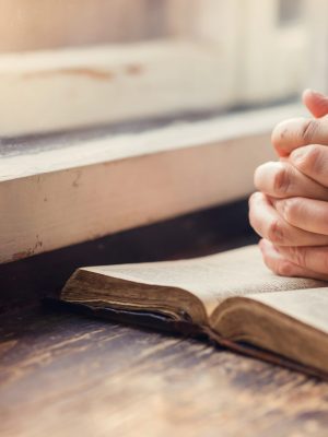 Hands,Of,An,Unrecognizable,Woman,With,Bible,Praying