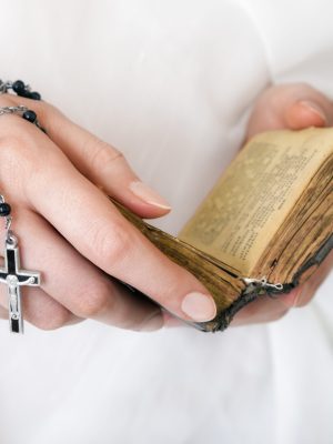Young,Woman's,Hands,With,A,Rosary,,Bible,And,A,White